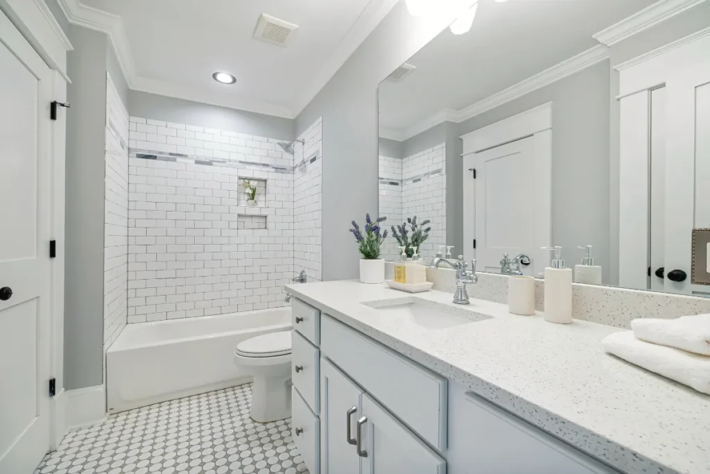 Bright bathroom with white vanity, mirror, and tiled shower