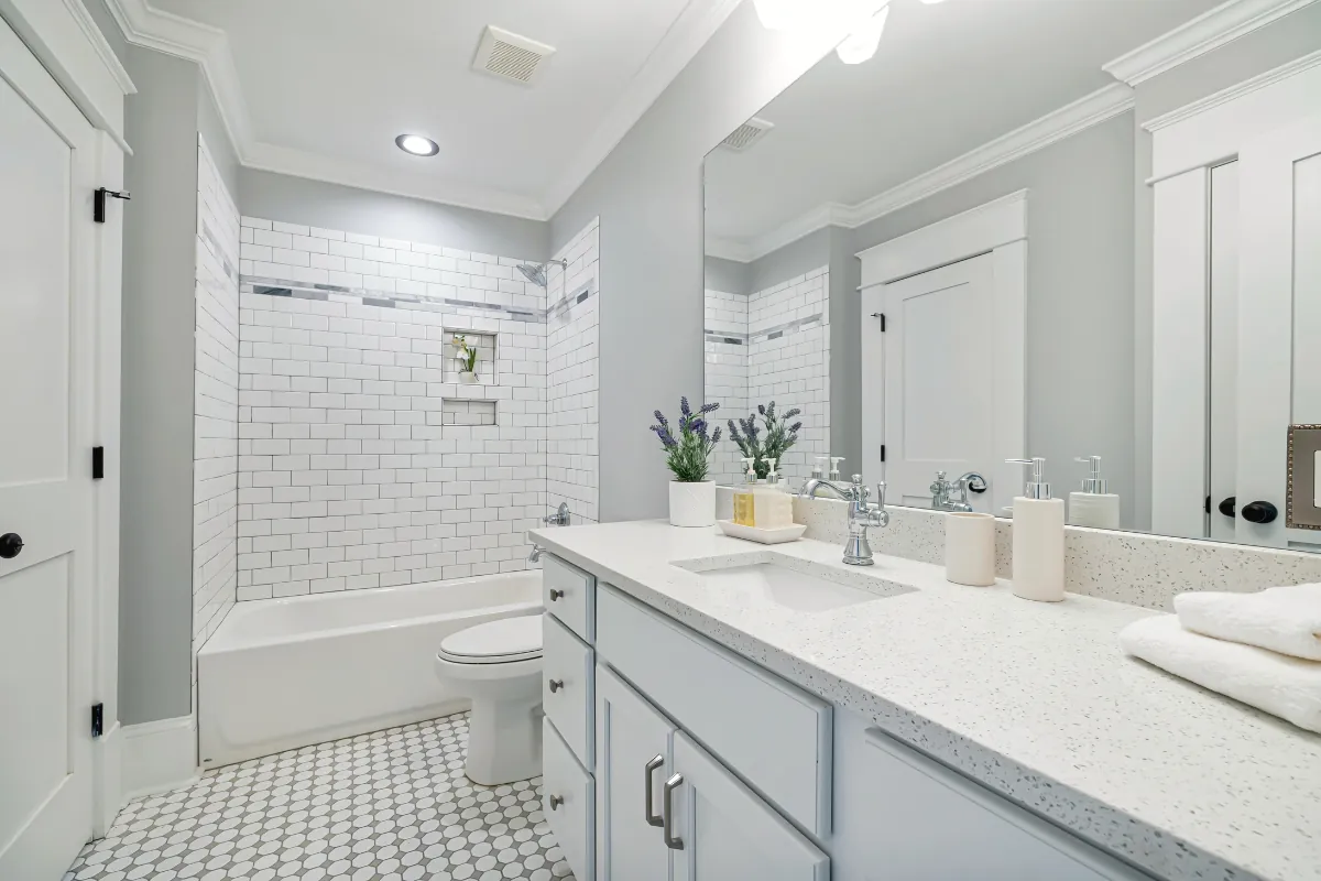 Bright bathroom with white vanity, mirror, and tiled shower