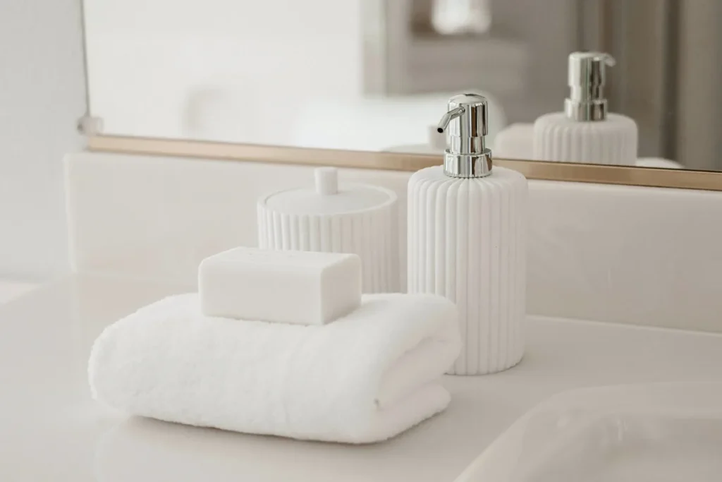 White soap bar on a folded towel beside bathroom accessories on a clean counter