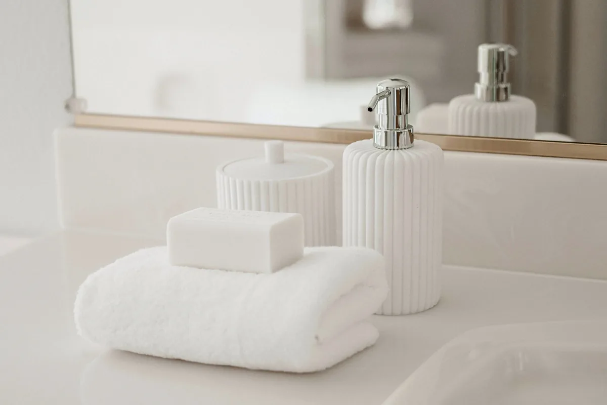 White soap bar on a folded towel beside bathroom accessories on a clean counter