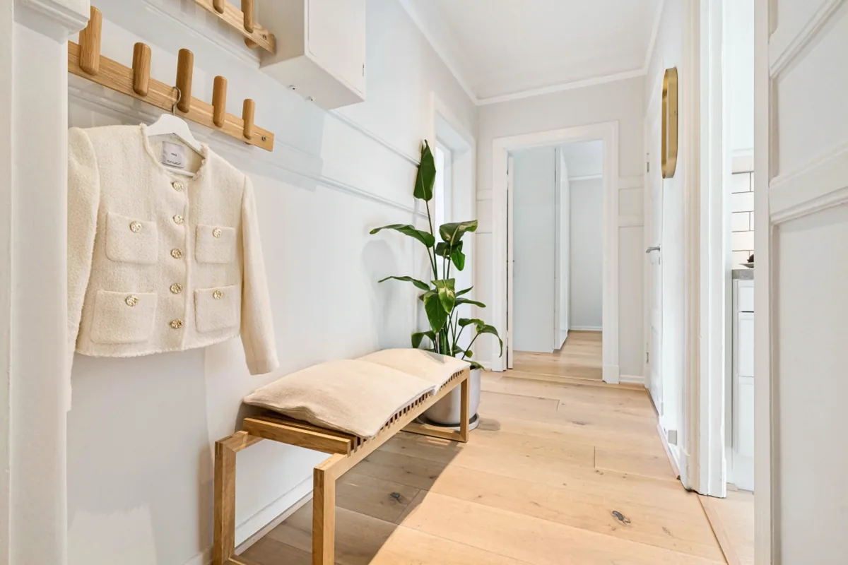 Organized entryway with wooden bench, coat hooks, and plant