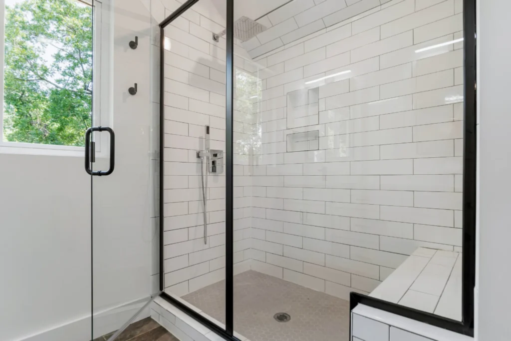 Clean glass shower with black frame in a bright white bathroom