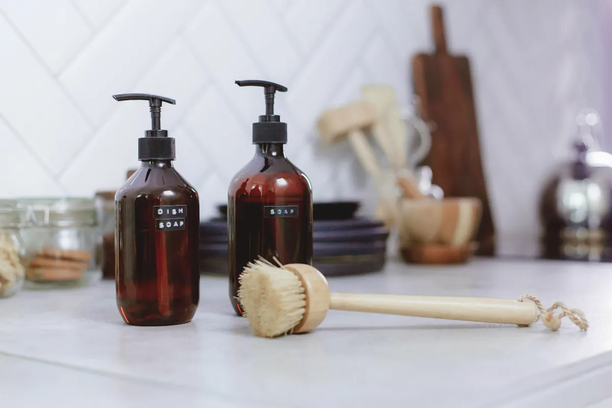 Dish soap bottles and a wooden brush on a kitchen counter