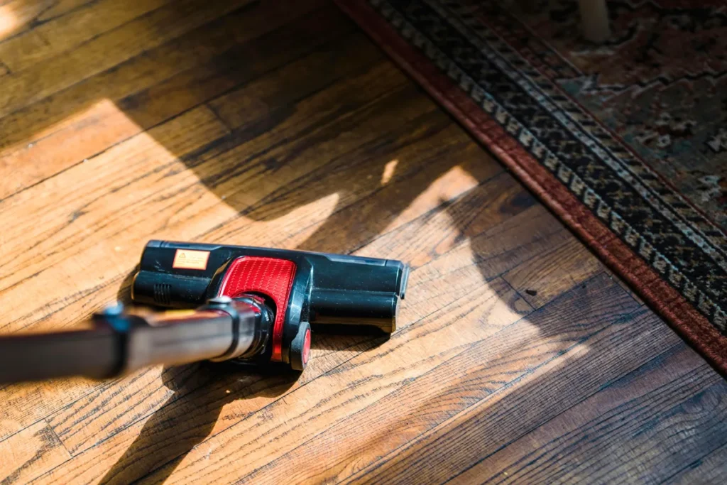 Vacuum head cleaning near a rug on a hardwood floor
