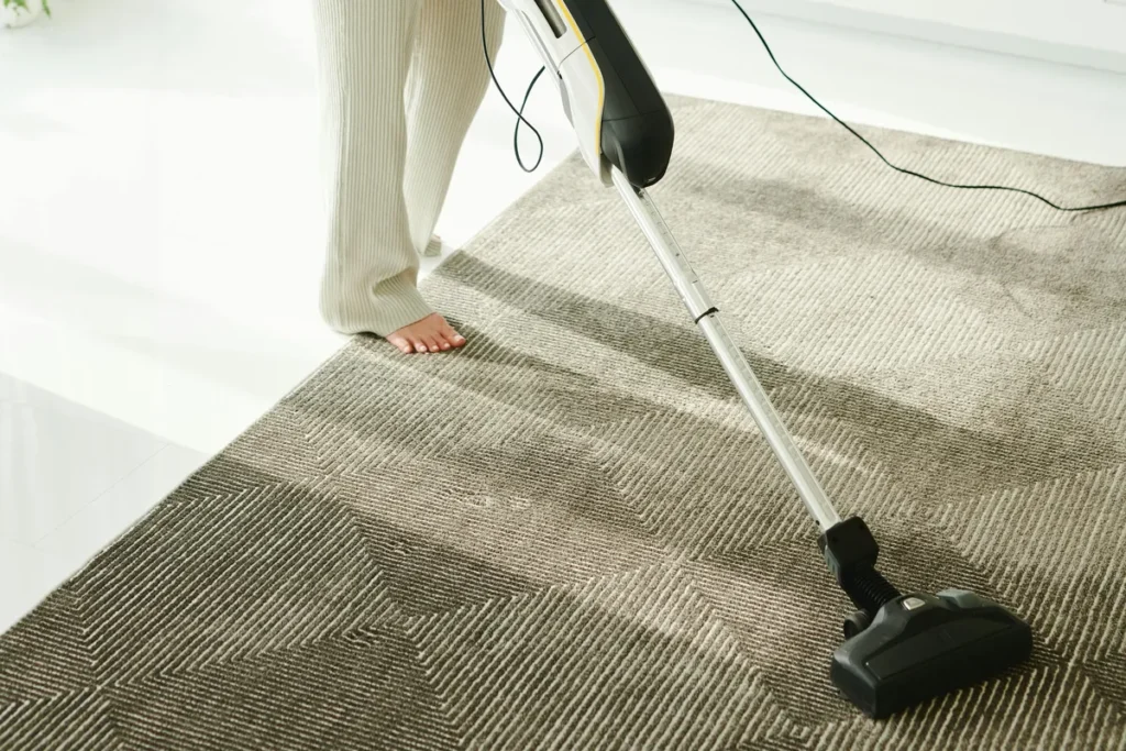Vacuum cleaning a rug in a bright living room