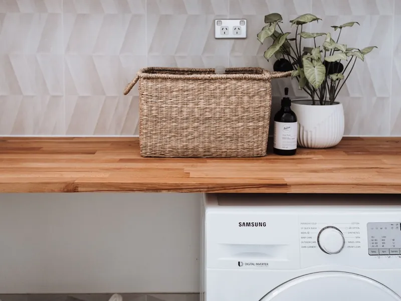 Bright laundry area with a wicker basket, houseplant, and washing machine