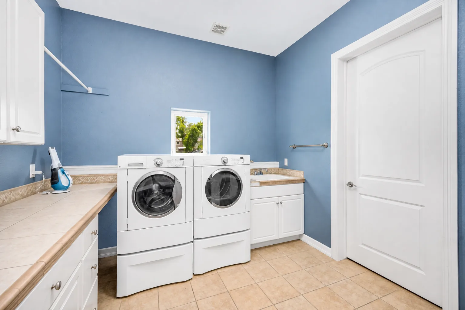 bright laundry room with white washer and dryer, blue walls, and built-in cabinets
