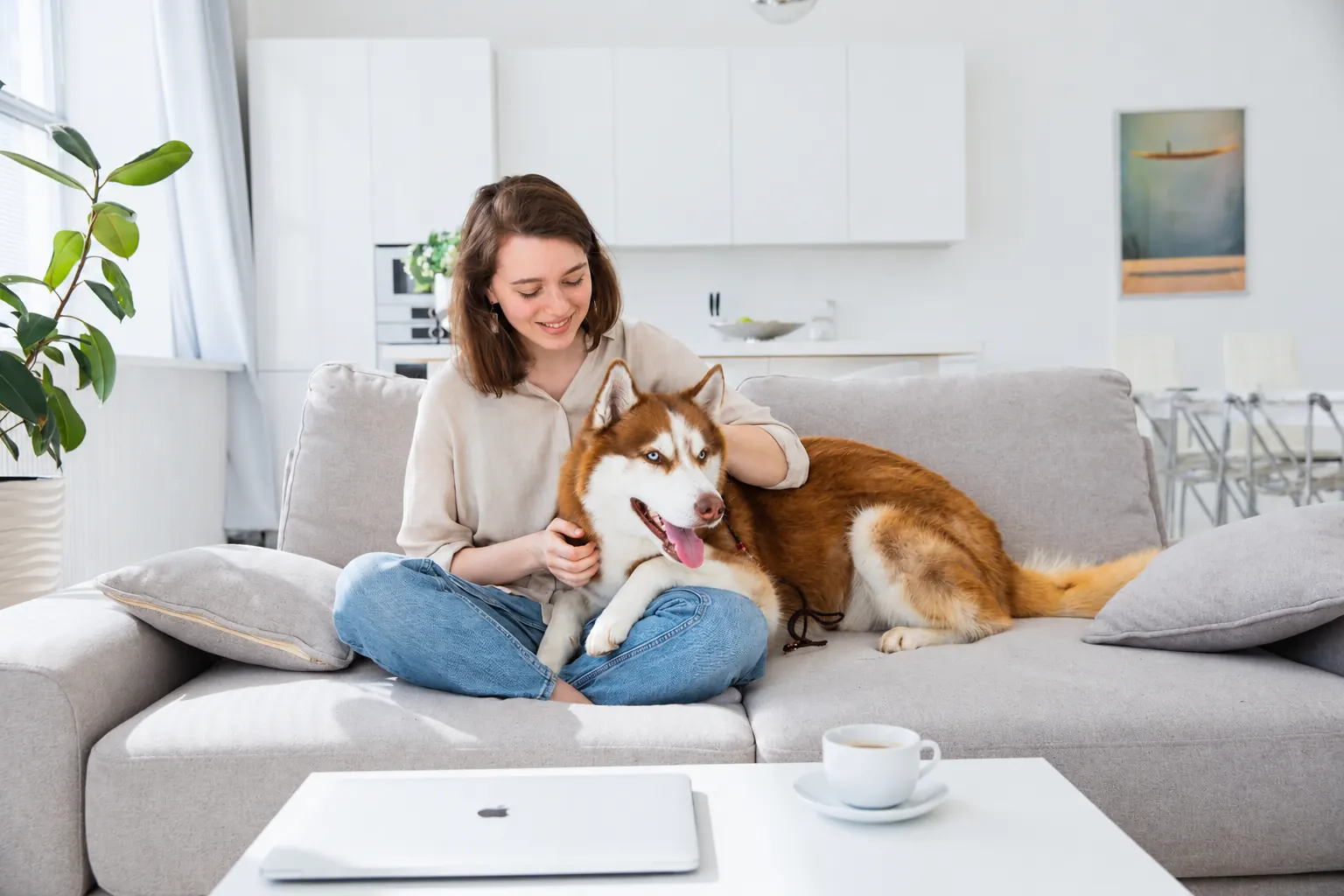 woman relaxing with a husky on a sofa in a bright pet-friendly living room